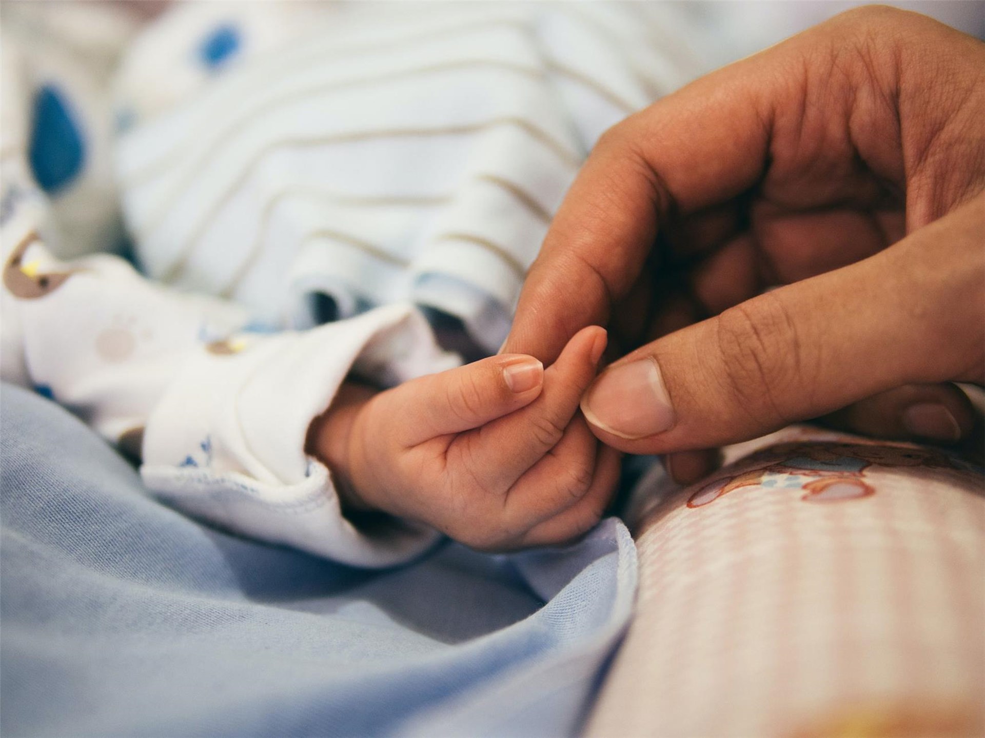 Eine Hand hält die winzige Hand eines Babys